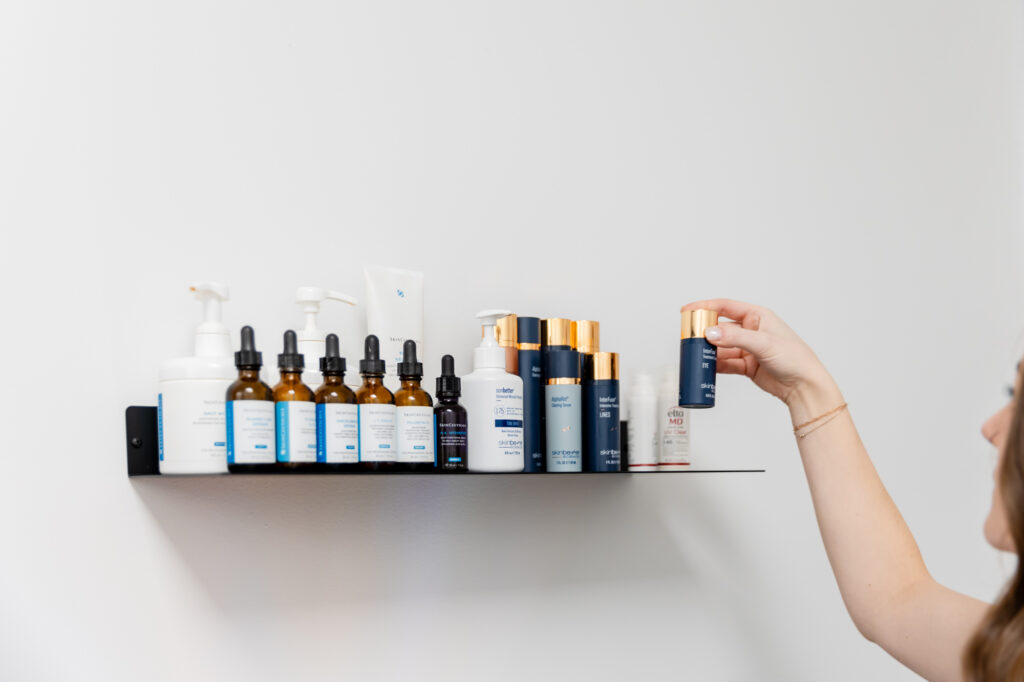 A woman picks up a skincare product from a shelf to use for dry skin treatments in Denver, CO